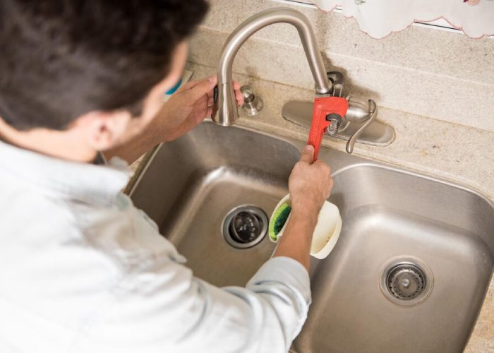 Man sitting near an open dishwasher and tools