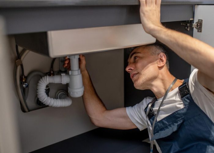 Man sitting near an open dishwasher and tools